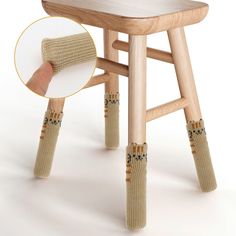 a wooden stool with socks on it and a hand reaching for the seat cushion that is attached