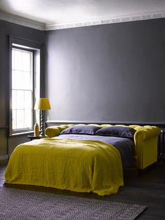 a yellow bed in a bedroom next to a window