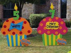 two birthday cupcakes with candles on them in front of a brick building and lawn