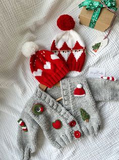 two knitted hats and mittens are laying on a bed next to christmas presents