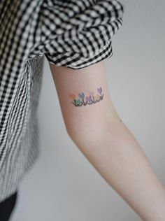 a person with a tattoo on their arm that says hello kitty and has flowers all over it