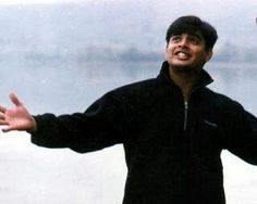 a man holding a frisbee in his hands while standing next to the ocean