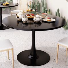 a black table with white chairs around it and plates of food on the table top