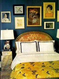 a bedroom with blue walls and pictures on the wall above the bed, along with a yellow bedspread