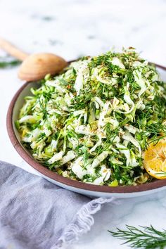 a bowl filled with shaved cabbage and lemon wedges