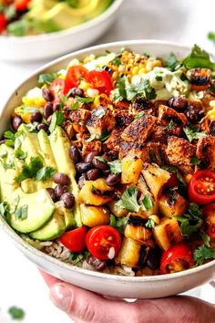 a bowl filled with mexican food and garnished with cilantro, black beans, avocado, corn