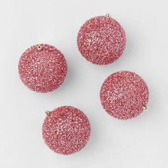 three pink glittered ornaments on a white surface