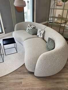 a curved couch sitting on top of a hard wood floor next to a table and chair