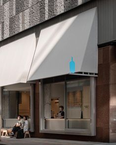 two people sitting on benches in front of an apple store with awnings over the windows