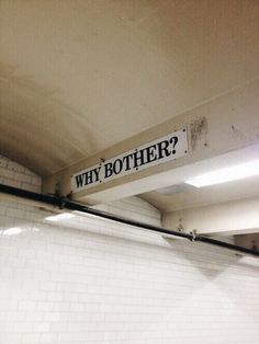 a sign that says, why brother? hanging from the ceiling in a subway station