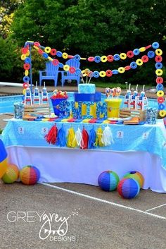 an outdoor party with balloons, streamers and cake on a table in the middle