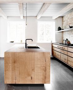 a kitchen with an island in the middle and wooden cabinets on both sides, along with white walls