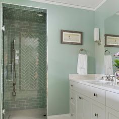 a bathroom with two sinks, a shower and green tiles on the wall in it