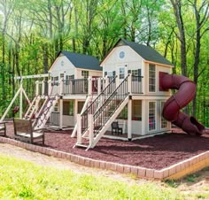 a small house with a slide in the front and two story houses on each side