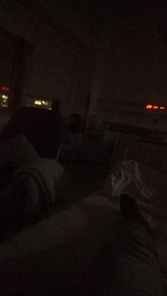 two people are sitting in the dark watching tv