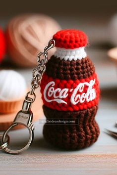 a crocheted coca cola bottle keychain sitting on top of a table