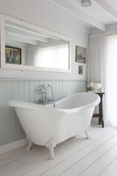 a white bath tub sitting under a bathroom mirror