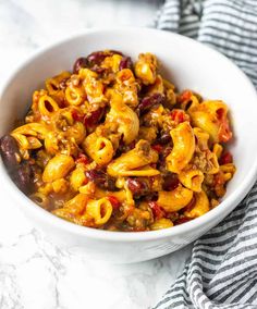 a white bowl filled with chili macaroni salad on top of a marble counter