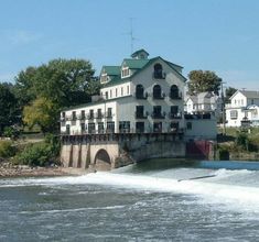 a large white building sitting on the side of a river next to a small bridge