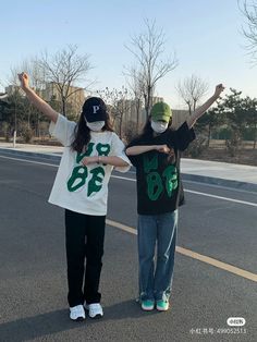 two young people standing on the side of a road with their arms in the air