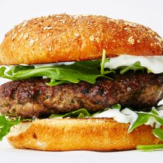 a hamburger with meat, lettuce and cheese on it sitting on a white surface