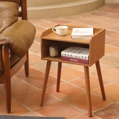 a small wooden table with a book on it next to a chair and coffee cup