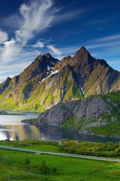 the mountains are covered in snow and green grass, with a road running between them