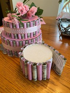 a cake made out of rolled up money and pink flowers on top of each other