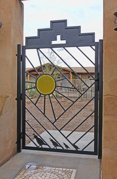 an iron gate with a yellow circle in the center and two birds sitting on it