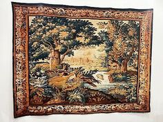 an old tapestry hanging on the wall next to a white wall with trees and animals