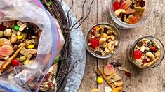 three glass containers filled with trail mix on top of a wooden table