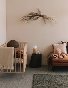 a baby's room with a crib, chair and stuffed animal on the floor