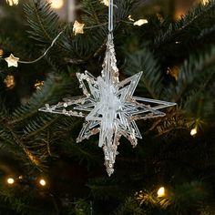 a clear snowflake ornament hanging from a christmas tree