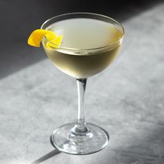 an alcoholic drink in a coupe glass with a lemon garnish