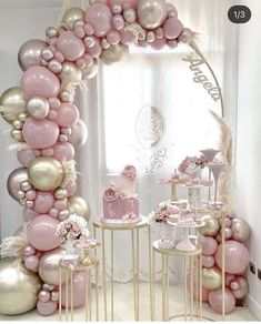 a pink and gold birthday party with balloons on the wall, cake table and chairs