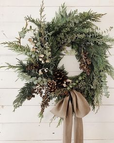 a christmas wreath with pine cones and greenery