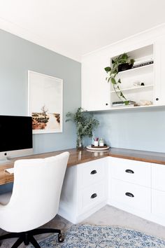 a desk with a computer on top of it in front of a wall mounted monitor