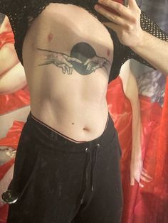 a woman with a tattoo on her stomach taking a selfie in front of a mirror