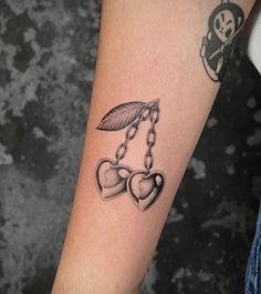 a tattoo on the arm of a woman with two heart shaped lockes hanging from chains