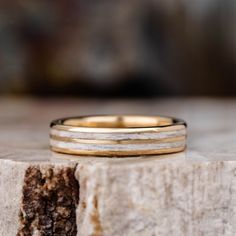 two wedding bands sitting on top of a piece of wood