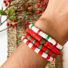 a close up of a person's arm wearing bracelets with red, green and white beads