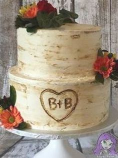 a three layer cake decorated with flowers and initials