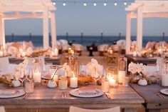 an outdoor dining area with candles, plates and napkins set up on the table