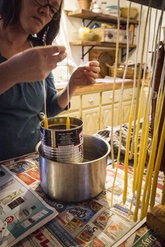 a woman is making noodles in a pot on the kitchen counter with yellow sticks sticking out of it