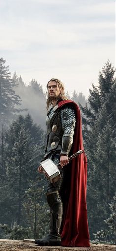 a man dressed as thor stands in front of some trees