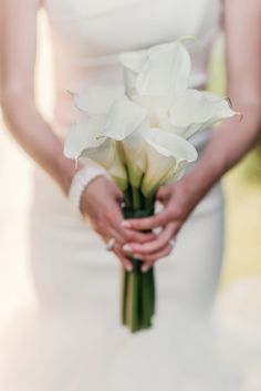 a bride holding a bouquet of white flowers