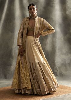 Editor's Note Silver Gold Striped Ghera Lampi Jacket With Gold Chanderi, Metallic Godet Inserts Double Tier Skirt. The Blouse Is Made Out Of Gold Lampi. Fabric: Chanderi Color: Gold Silver Care: Dry Clean Only About the Designer Itrh makes a high-end luxury Indian ethnic wear made using exquisite and endangered age-old crafts such as kalamkari, madhubani, chikankari, zardozi, and gota weaving. The focus of the house is to cherish the beauty of handcrafted luxury designer wear. Luxury Bollywood Zari Work Skirt Set, Luxury Cream Traditional Wear With Gold Embroidery, Luxury Artistic Dupatta With Traditional Drape, Luxury Chanderi Party Wear Choli, Luxury Gold Art Silk Palazzo Set, Luxury Gold Anarkali Set For Party, Luxury Traditional Party Wear With Gold Embroidery, Luxury Traditional Georgette Wear, Luxury Georgette Choli For Transitional Season