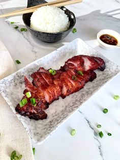 some meat is on a plate with rice and chopsticks