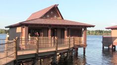 two people are standing on a dock next to a building that is built into the water