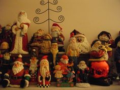 a group of santa claus figurines sitting on top of a shelf next to a christmas tree